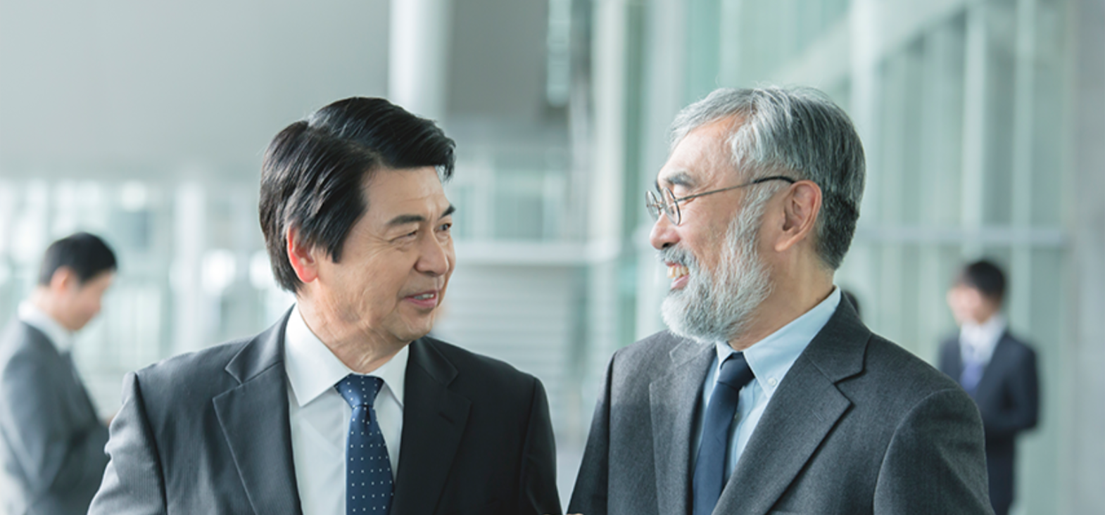 Two Japanese businessmen smiling while standing